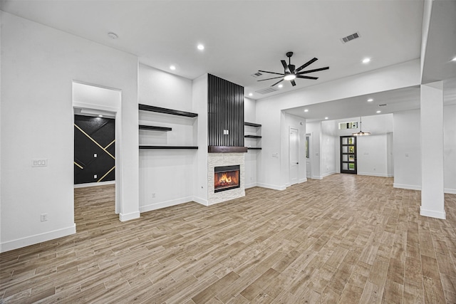 unfurnished living room featuring light wood finished floors, recessed lighting, visible vents, and a stone fireplace