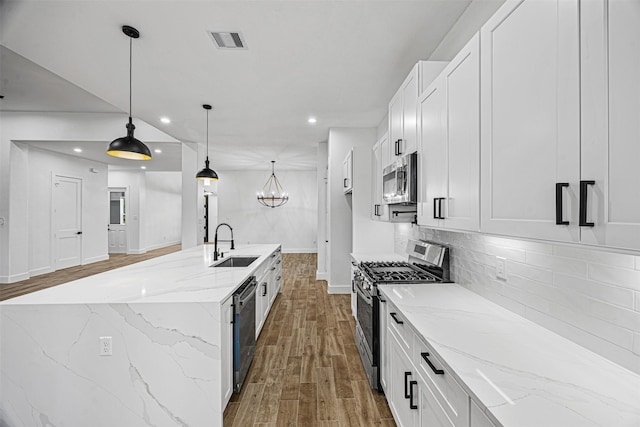 kitchen with light stone counters, visible vents, white cabinetry, hanging light fixtures, and appliances with stainless steel finishes