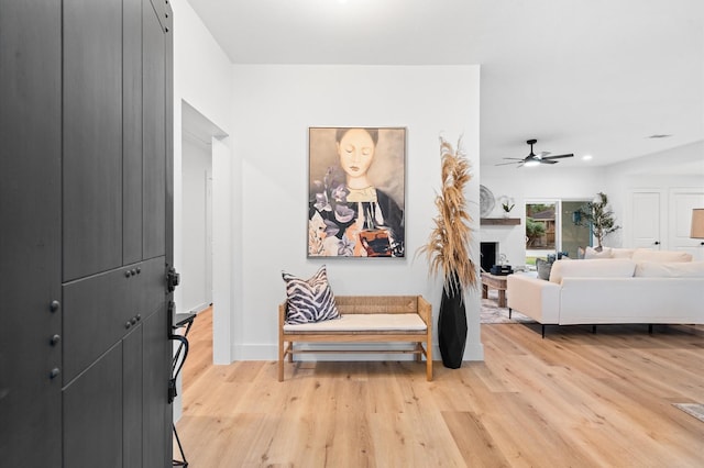 interior space with light wood finished floors, a fireplace, and a ceiling fan