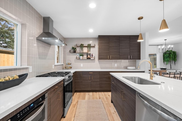 kitchen featuring appliances with stainless steel finishes, sink, backsplash, light wood-type flooring, and wall chimney exhaust hood