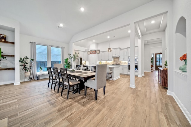 dining room featuring vaulted ceiling and light hardwood / wood-style flooring