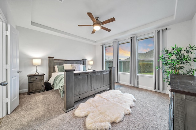 bedroom with a tray ceiling, carpet flooring, and ceiling fan