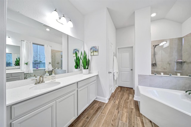 bathroom with shower with separate bathtub, vaulted ceiling, and vanity