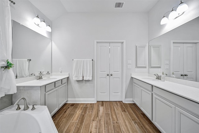 bathroom with lofted ceiling, vanity, and hardwood / wood-style floors