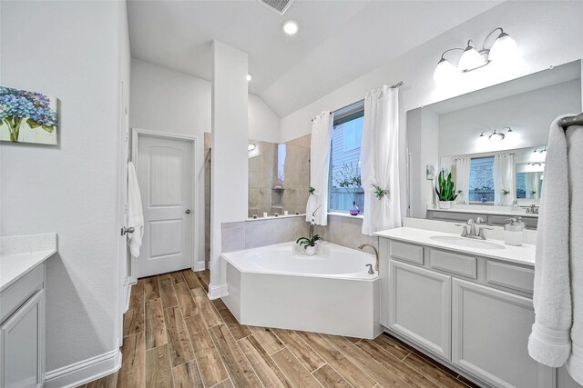 bathroom featuring vanity, a tub to relax in, and lofted ceiling