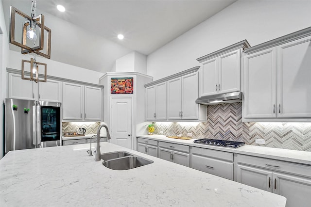 kitchen with appliances with stainless steel finishes, light stone counters, decorative light fixtures, gray cabinets, and sink