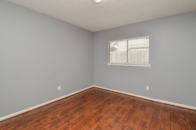 spare room with baseboards and wood finished floors