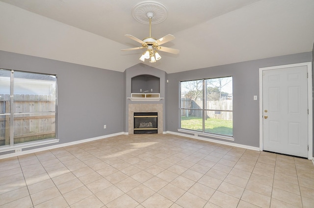 unfurnished living room featuring light tile patterned floors, a tiled fireplace, vaulted ceiling, ceiling fan, and baseboards