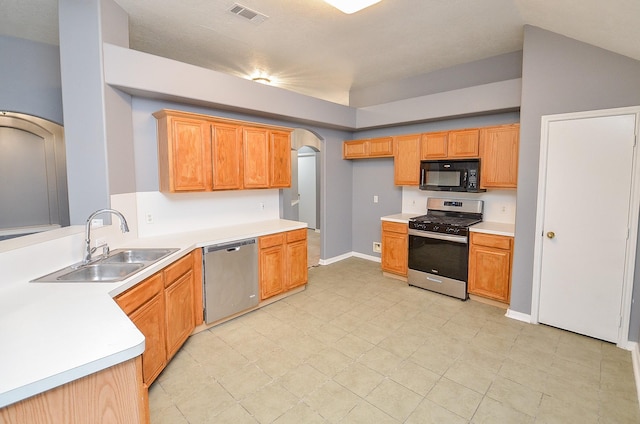 kitchen with arched walkways, stainless steel appliances, light countertops, visible vents, and a sink