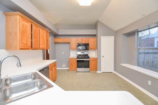 kitchen featuring lofted ceiling, stainless steel appliances, a sink, baseboards, and light countertops