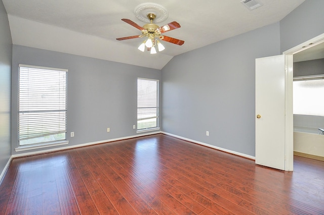 spare room featuring lofted ceiling, dark wood-style floors, baseboards, and visible vents