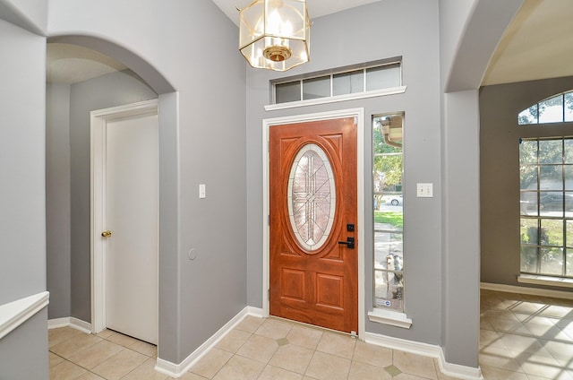 entryway with baseboards, arched walkways, and light tile patterned flooring