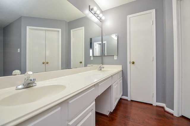 bathroom featuring double vanity, a sink, baseboards, and wood finished floors