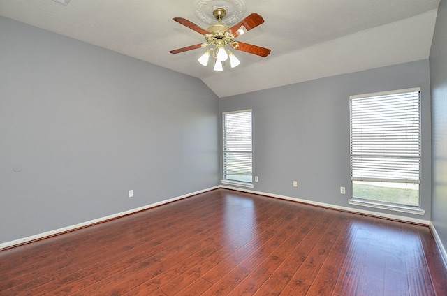 unfurnished room with a healthy amount of sunlight, baseboards, dark wood finished floors, and lofted ceiling