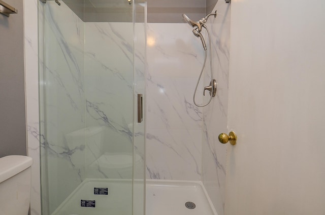 full bathroom with toilet and a marble finish shower