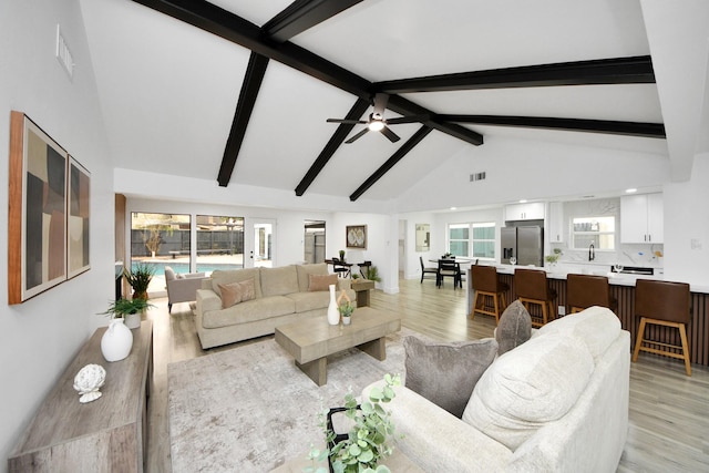 living room with light wood-type flooring, high vaulted ceiling, and plenty of natural light