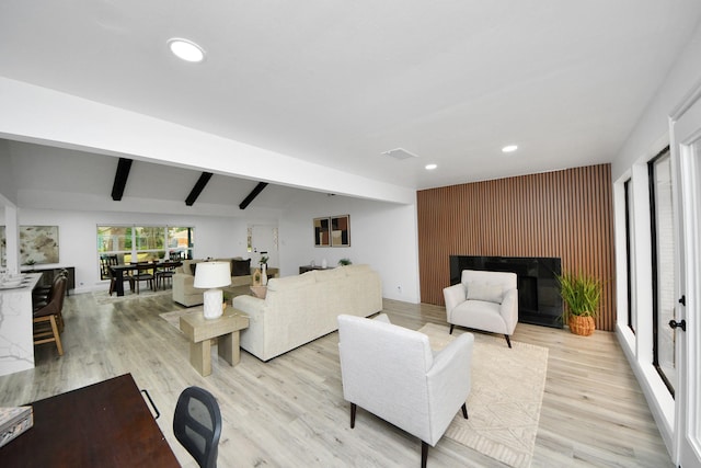 living room featuring light wood-type flooring and beamed ceiling