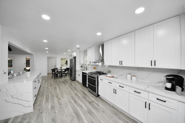 kitchen featuring white cabinetry, appliances with stainless steel finishes, light stone countertops, and wall chimney exhaust hood