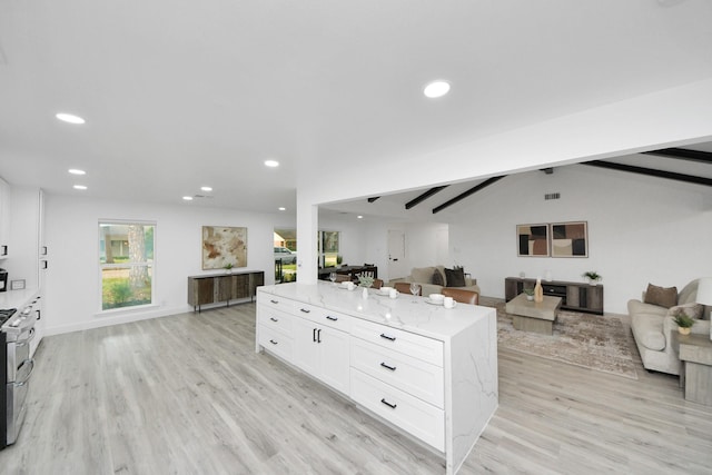 kitchen with vaulted ceiling with beams, light stone countertops, white cabinets, light hardwood / wood-style floors, and a center island