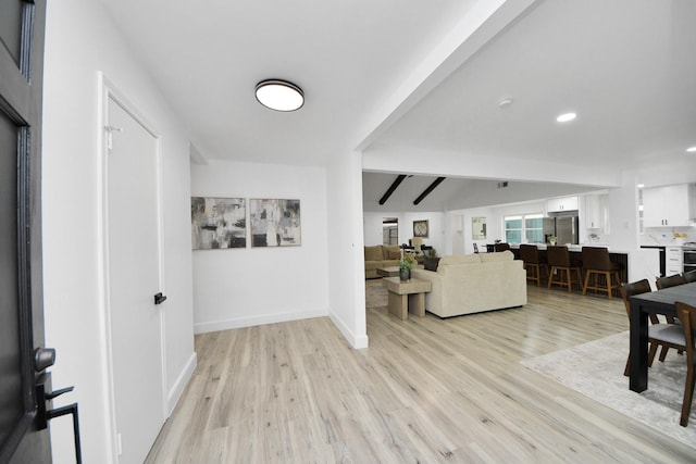 interior space with light wood-type flooring and vaulted ceiling with beams