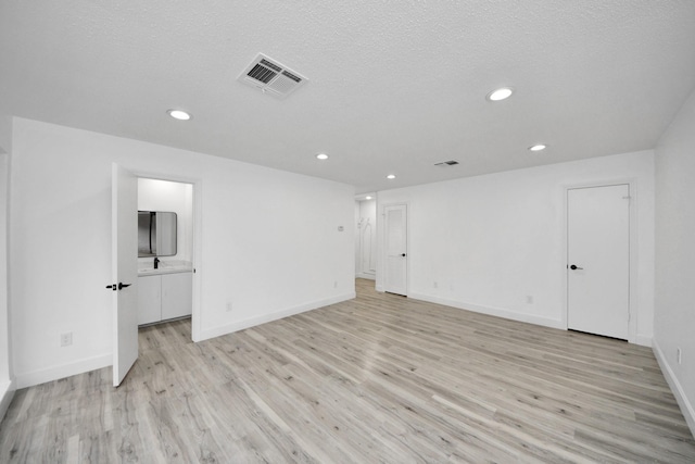 unfurnished room with a textured ceiling and light hardwood / wood-style floors