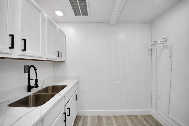 kitchen with light hardwood / wood-style flooring, sink, white cabinetry, and light stone countertops