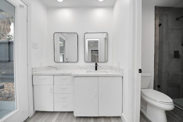 bathroom featuring hardwood / wood-style flooring, vanity, toilet, and walk in shower