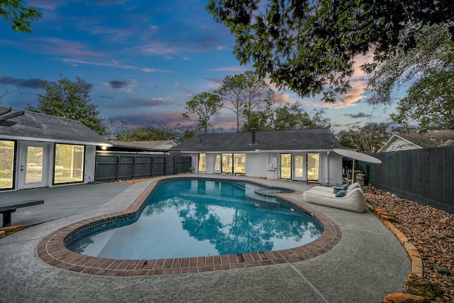 pool at dusk featuring a patio