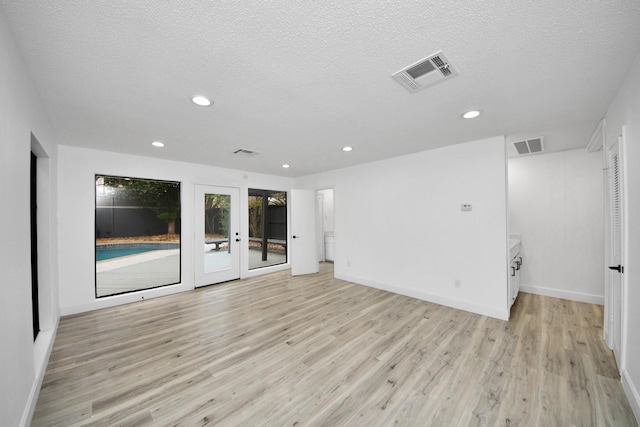 empty room with light wood-type flooring and a textured ceiling