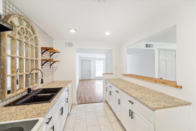 kitchen featuring white range with electric cooktop, light stone countertops, white cabinets, light tile patterned flooring, and sink