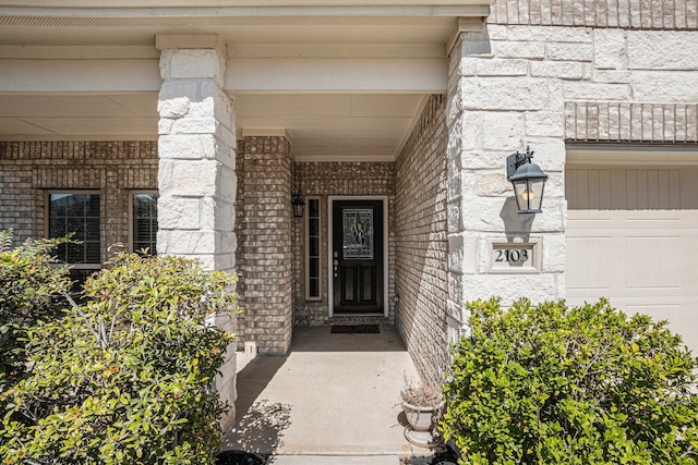 doorway to property with a garage and brick siding