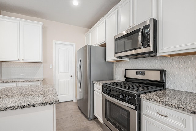 kitchen with white cabinets, light tile patterned floors, stainless steel appliances, and light stone countertops