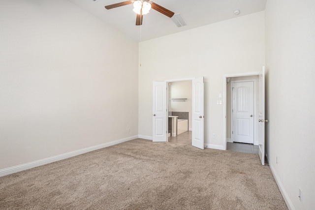 unfurnished bedroom with ensuite bath, high vaulted ceiling, baseboards, and light colored carpet