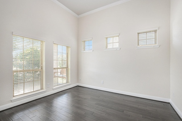 spare room featuring baseboards, dark wood finished floors, and crown molding