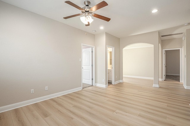 empty room with arched walkways, recessed lighting, a ceiling fan, light wood-type flooring, and baseboards