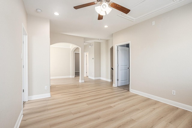 spare room featuring arched walkways, baseboards, light wood finished floors, and recessed lighting