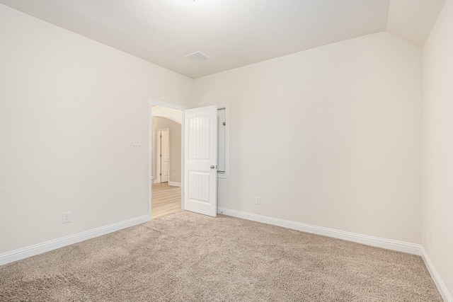 unfurnished room featuring light carpet, baseboards, arched walkways, and vaulted ceiling