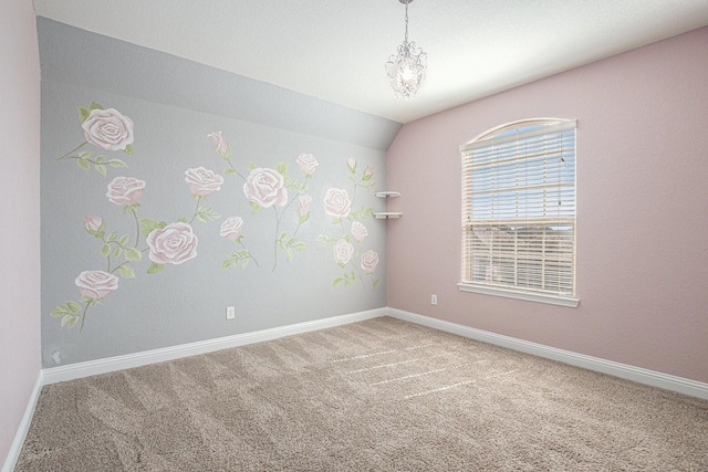 spare room featuring lofted ceiling, carpet flooring, and baseboards