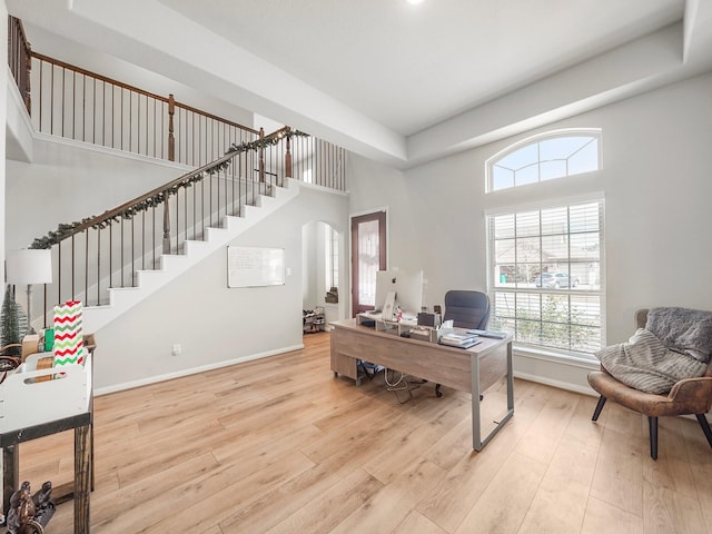 office with light hardwood / wood-style floors and a towering ceiling