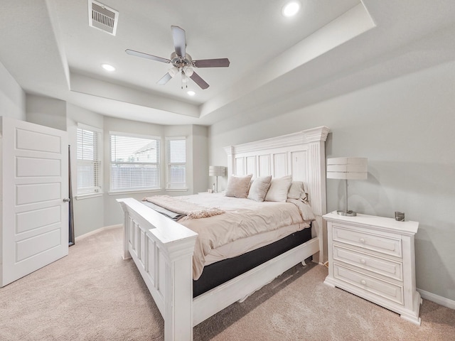 carpeted bedroom with ceiling fan and a raised ceiling