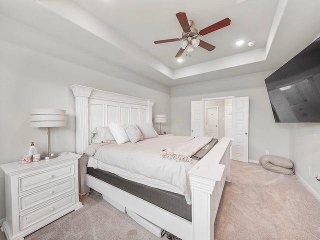 bedroom with light carpet, ceiling fan, and a tray ceiling