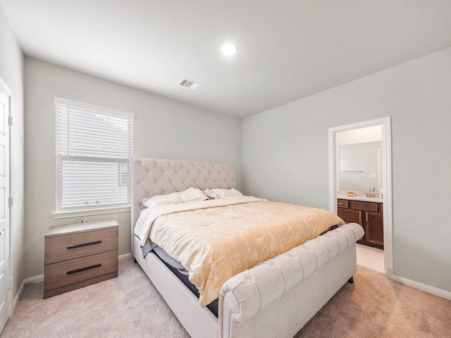 bedroom with light carpet and connected bathroom