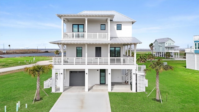 coastal home with a front lawn, a garage, a water view, and a balcony