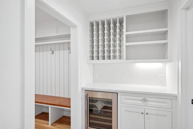 mudroom featuring beverage cooler, light wood finished floors, and a dry bar