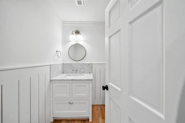 bathroom with visible vents, ornamental molding, wood finished floors, and vanity