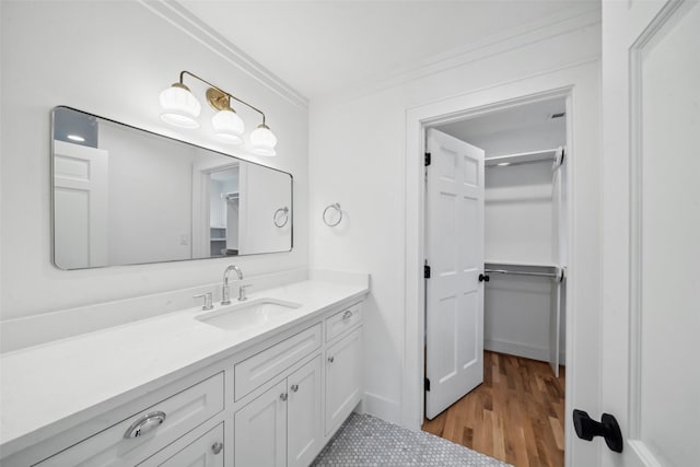 bathroom with ornamental molding, vanity, baseboards, and wood finished floors