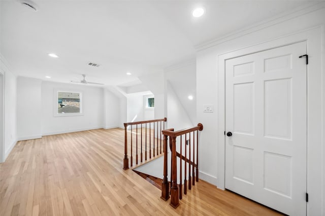 corridor with visible vents, baseboards, an upstairs landing, light wood-type flooring, and crown molding