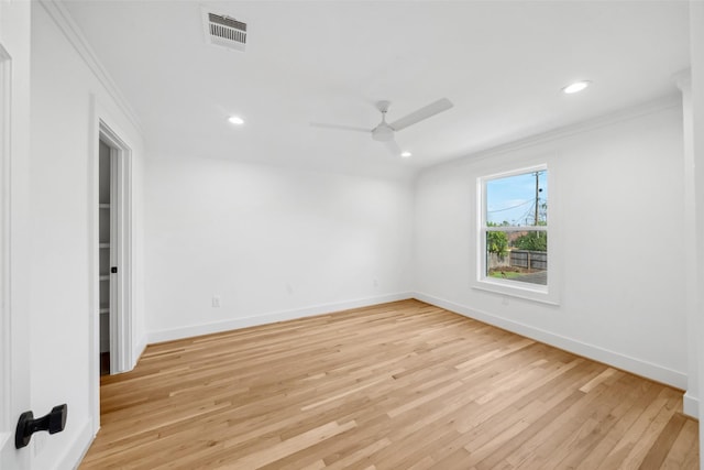 spare room with light wood-style flooring, visible vents, and crown molding