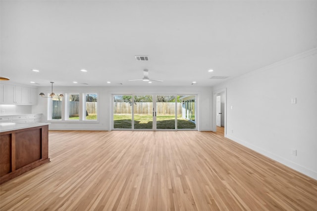 unfurnished living room with baseboards, ceiling fan, light wood-style flooring, and a healthy amount of sunlight