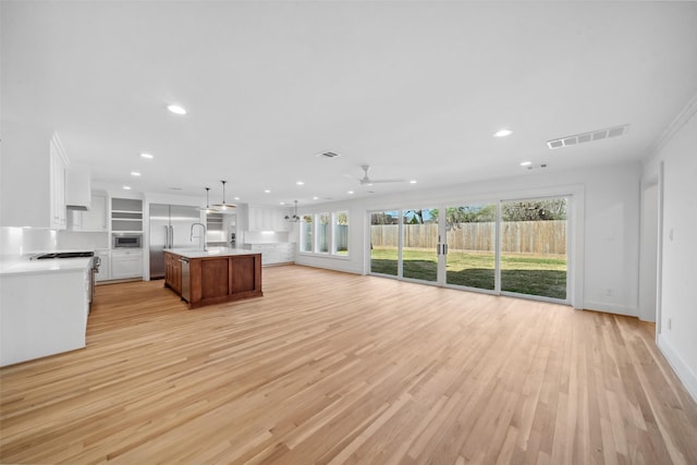 unfurnished living room with ceiling fan, recessed lighting, a sink, visible vents, and light wood-style floors